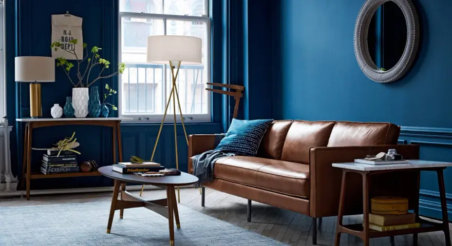 Ein Wohnzimmer mit braunem Ledersofa und blauen Wänden. Das Braun ist die perfekte gegenfarbe von braun, die dem Raum Tiefe verleiht.