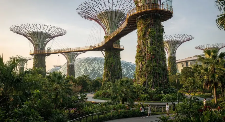 Futuristische Supertrees und Gewächshäuser in den Gardens by the Bay, Singapur, mit Menschen, die auf Wegen spazieren.