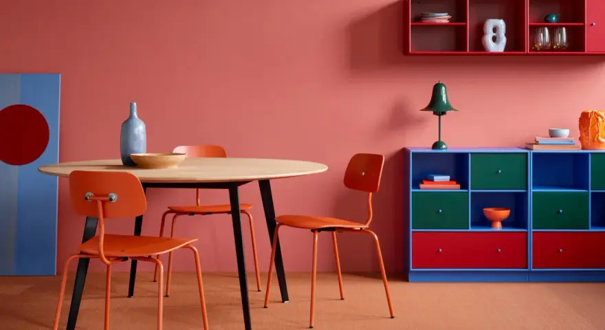 Ein Esszimmer mit roten Akzenten: Orange Stühle, ein blauer Schrank und rote Regale zeigen, welche Farben passen zu Rot.