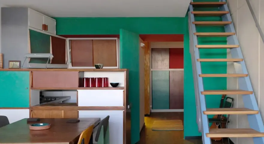 Einblick in eine Wohnung im Stil von Le Corbusier in Berlin: bunte Wände, Holzmöbel und eine Leiter.