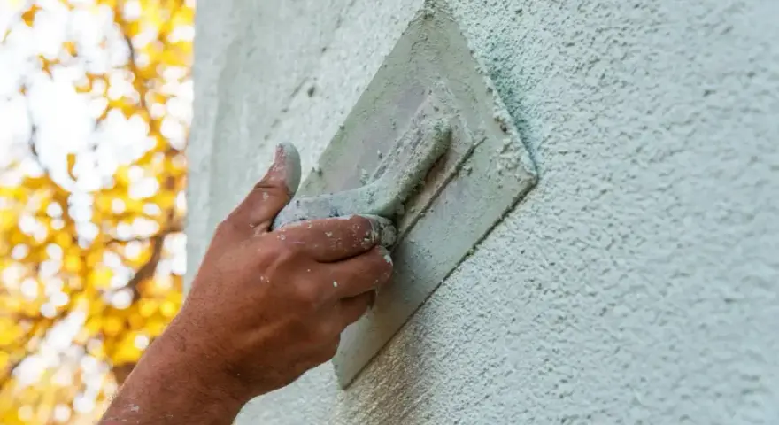 Hand bearbeitet eine Fassade mit einer Kelle. Verschiedene Putztechniken fassade werden hier angewendet, um eine rustikale Textur zu erzeugen.