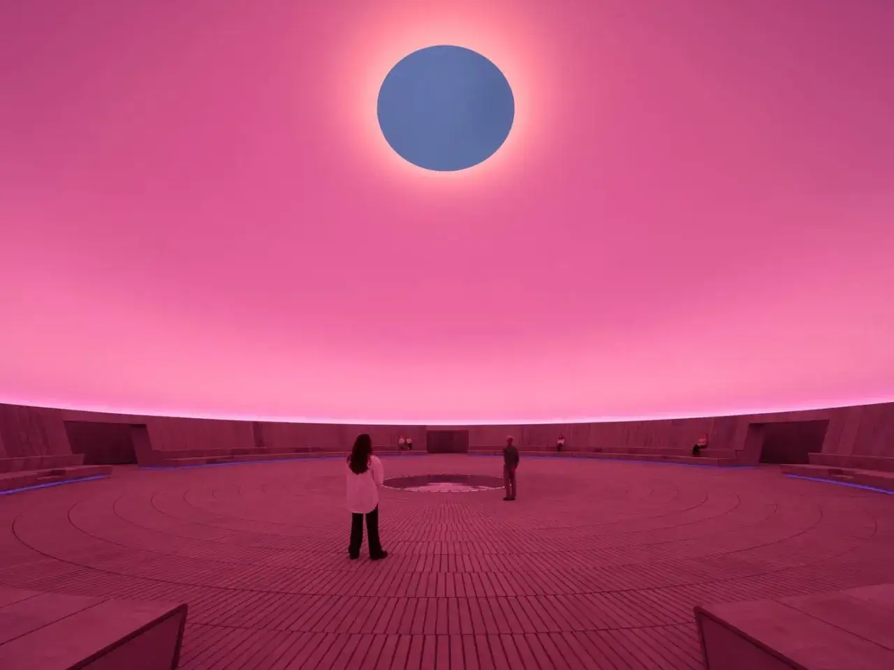 Im Kunstmuseum Aarhus erleben Besucher eine Installation mit rosa Himmel und einem blauen Kreis.