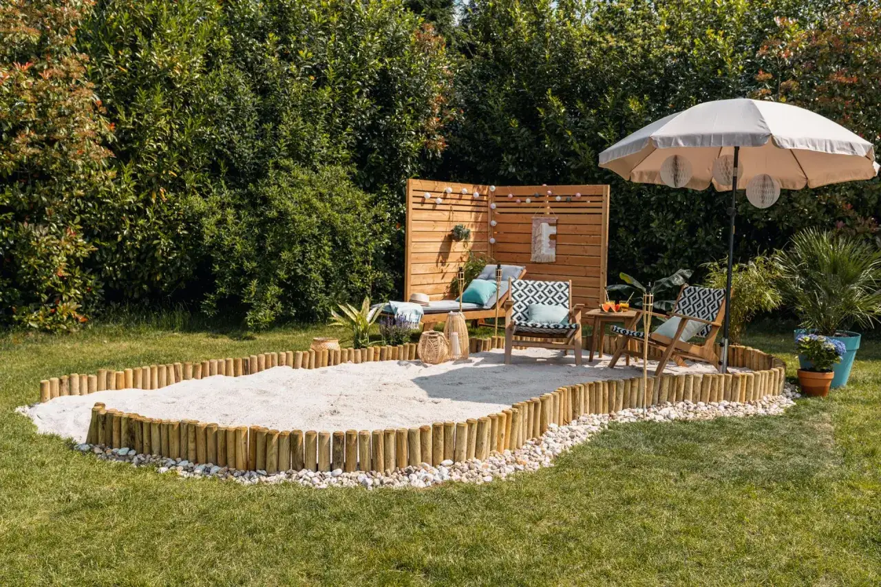 Ein Sandkasten mit Holzumrandung und Liegest&uuml;hlen sorgt f&uuml;r Strandfeeling im Garten. Sonnenschirm und Lichterkette laden zum Entspannen ein.