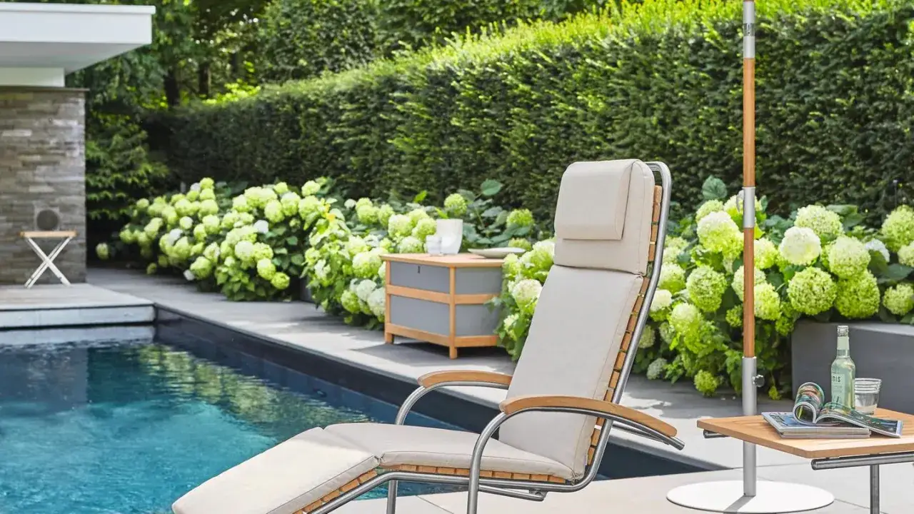 Entspannter Urlaub im eigenen Garten: moderne gartengestaltung mit pool und terrasse, Liegestuhl, Sonnenschirm und Hortensien.