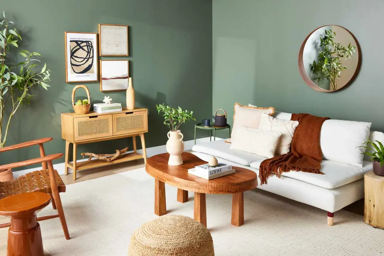 Gem&uuml;tliches Wohnzimmer mit Rattan-Kommode, ovalem Holztisch und wei&szlig;em Sofa. Ein Spiegel und Kunstwerke an der Wand schaffen eine harmonische Feng Shui Wohnung.