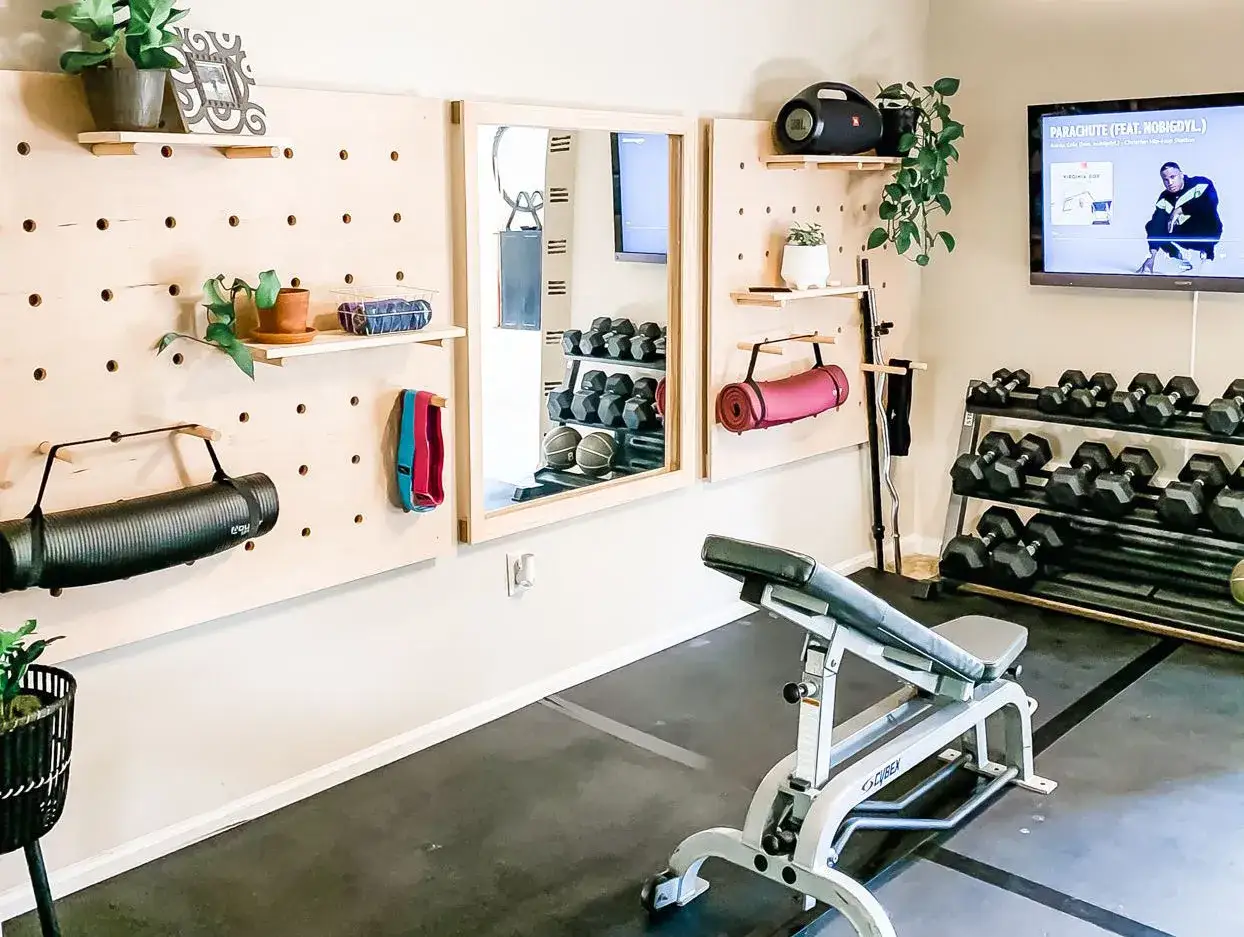Praktische home gym ideen: Hantelbank, Hantelst&auml;nder, Yogamatten und Pflanzen schaffen eine motivierende Trainingsatmosph&auml;re.