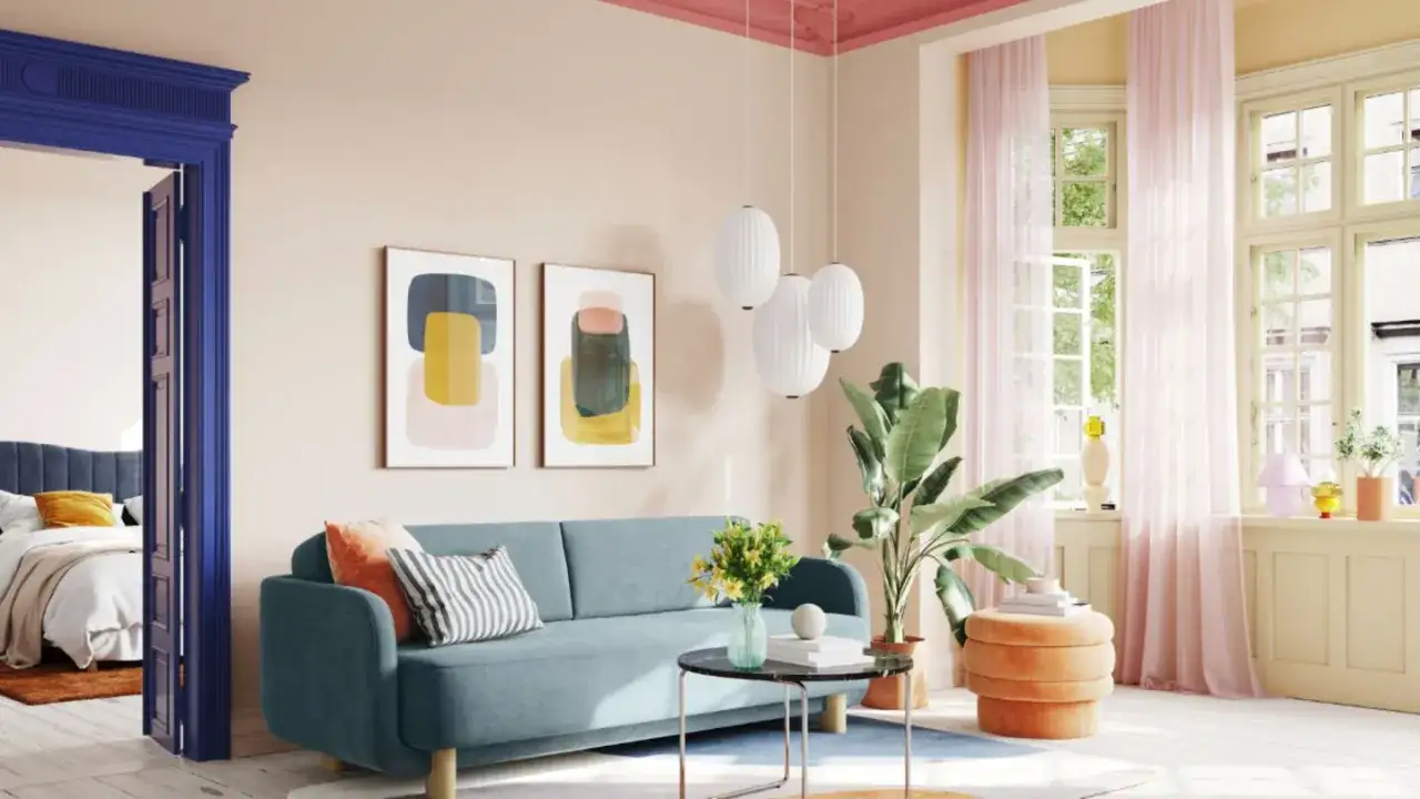 Ein helles Wohnzimmer mit einem blauen Sofa, Kunstwerken und einem orangefarbenen Hocker. Die Decke und Wand haben die gleiche Farbe, was für ein harmonisches Ambiente sorgt.