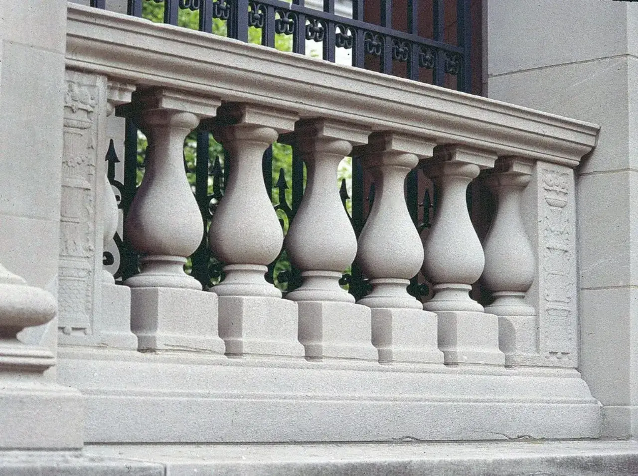 Eine Balustrade aus Stein mit kunstvollen S&auml;ulen und einem schmiedeeisernen Gitter dahinter.