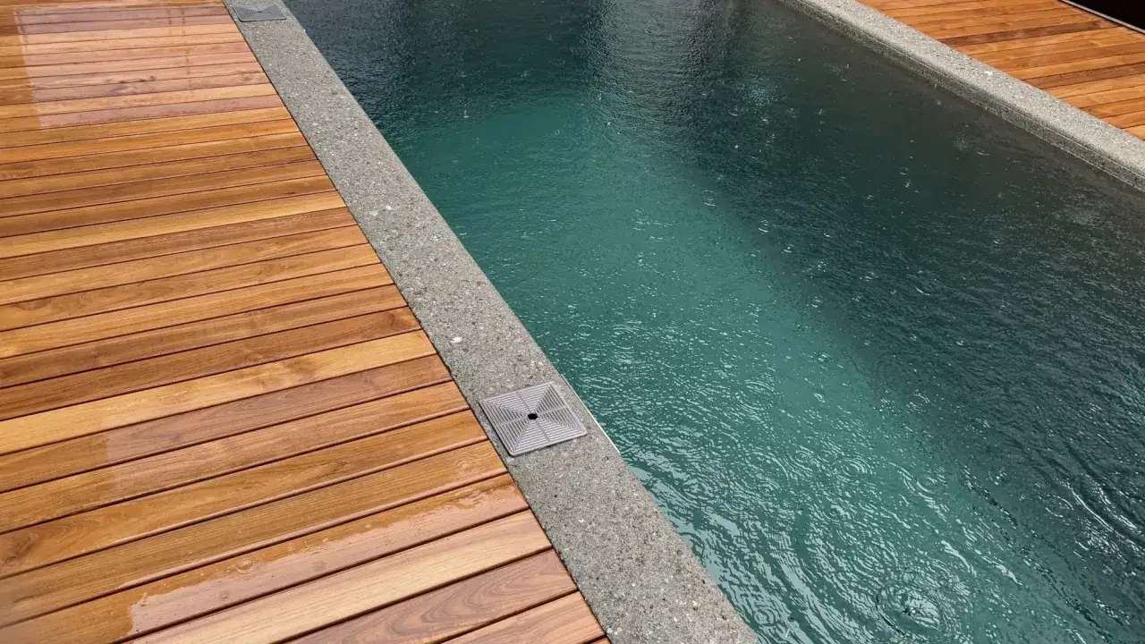 Holzdeck neben einem Pool am Hang. Ideen f&uuml;r einen modernen Pool mit Holzterrasse und Betonrand.
