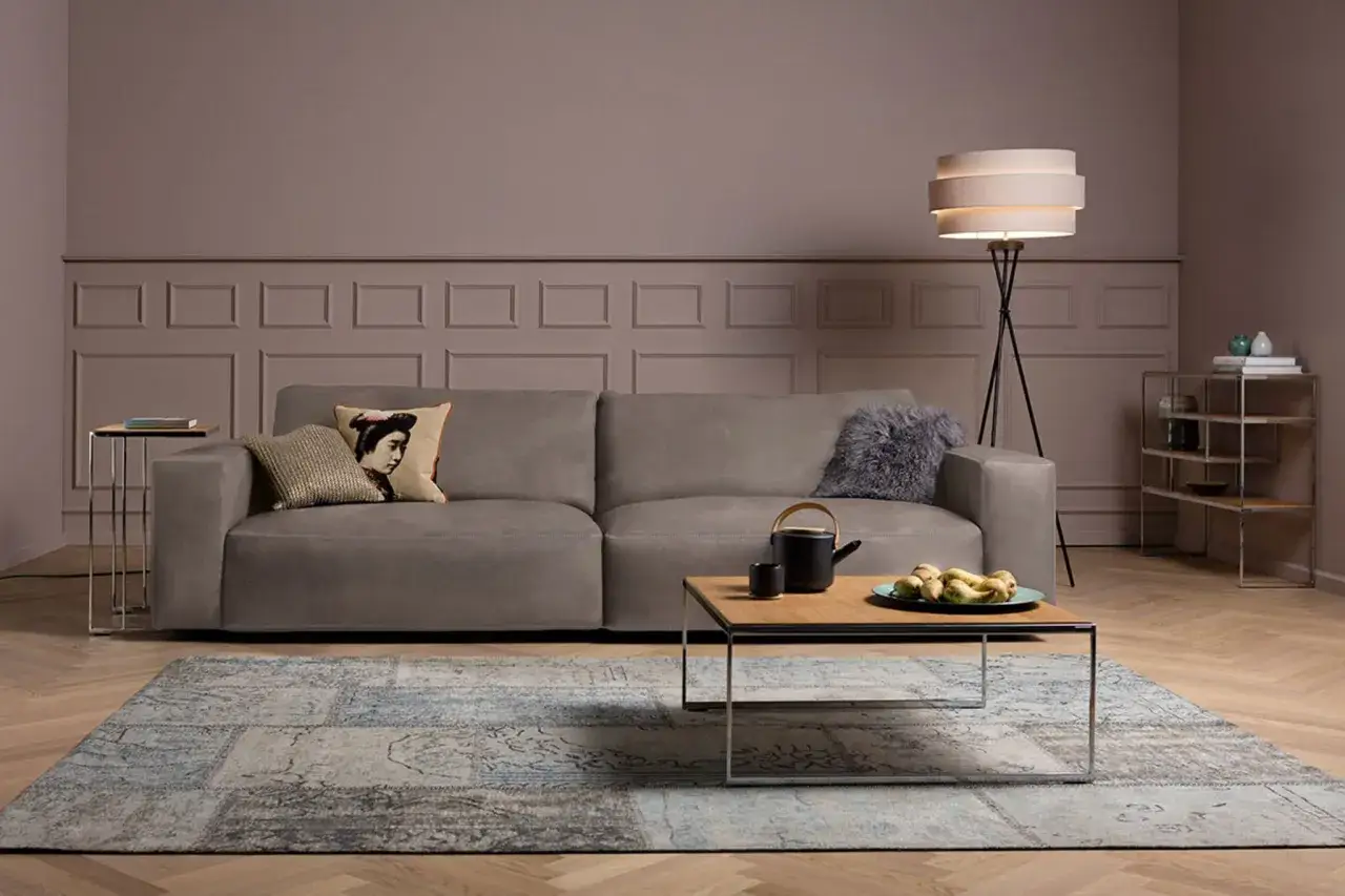 Ein taupefarbenes Sofa mit Kissen und ein Couchtisch mit Fr&uuml;chten. Welche Farbe passt zu Taupe? Blau und Grau harmonieren gut.