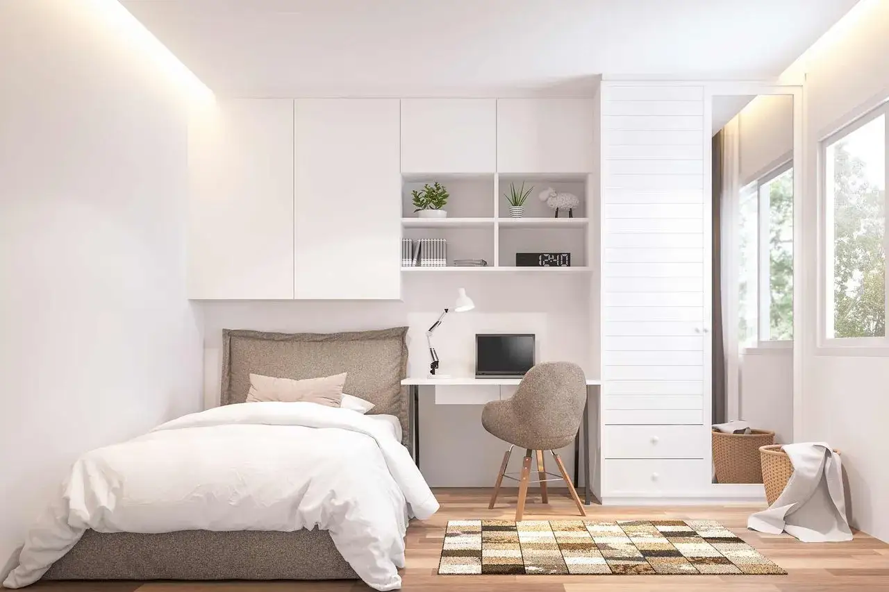 Moderne zimmer einrichten ideen: Ein weißes Bett, Schreibtisch mit Laptop und ein Kleiderschrank mit Spiegel.