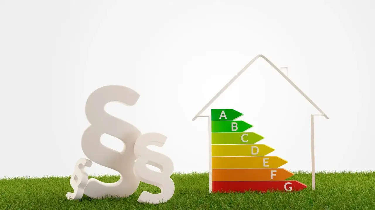 Paragraphenzeichen und Energieeffizienzhaus auf grünem Gras.