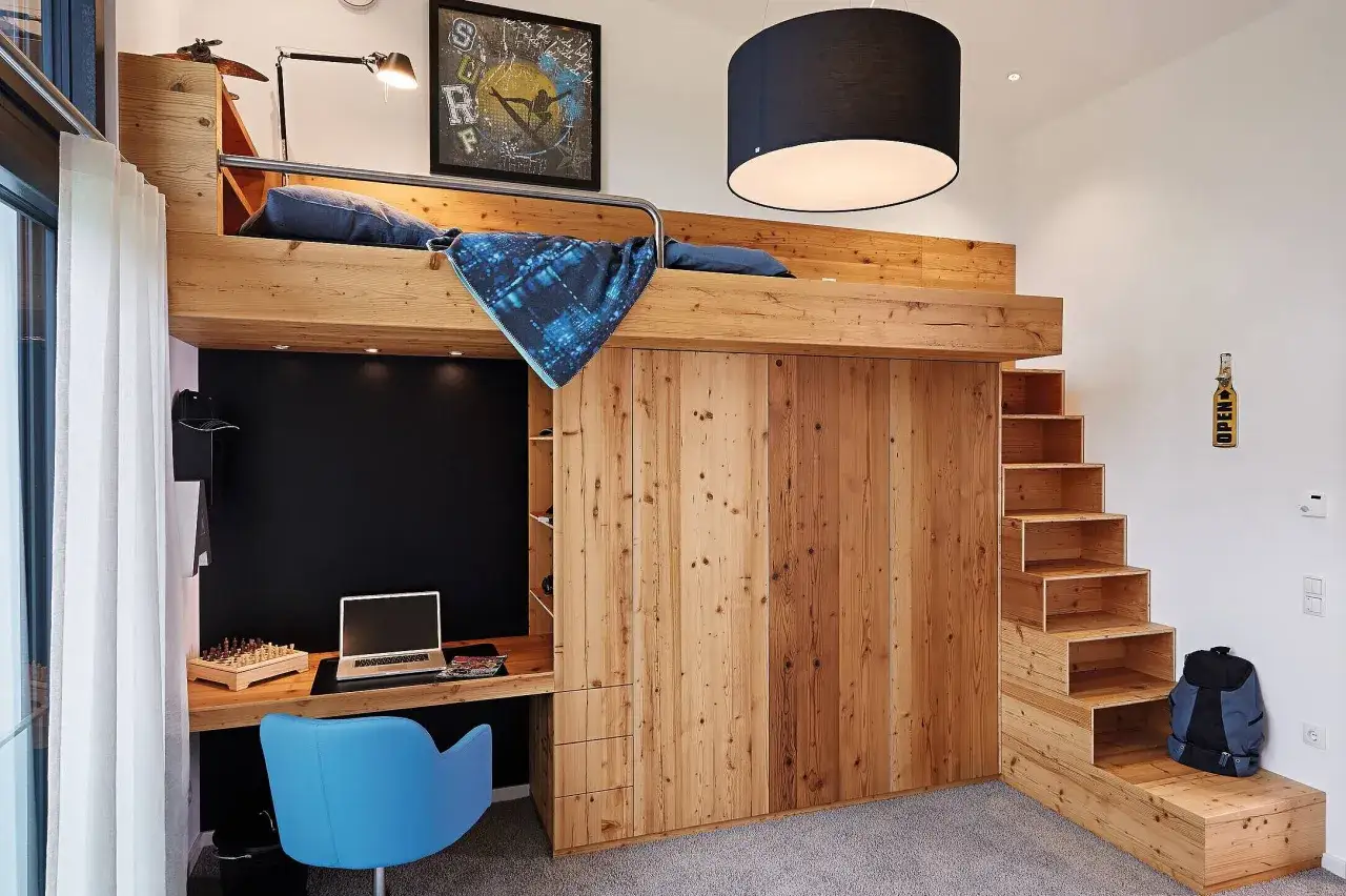 Gemütliches tiny house interior mit Hochbett, Schreibtisch und integrierten Stufen. Holzverkleidung schafft Wärme.