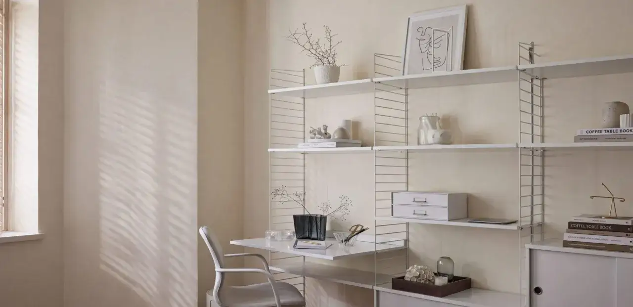 Ein helles, minimalistisches kleines Arbeitszimmer einrichten mit schwebendem Schreibtisch, wei&szlig;em Regal und einem bequemen Stuhl.