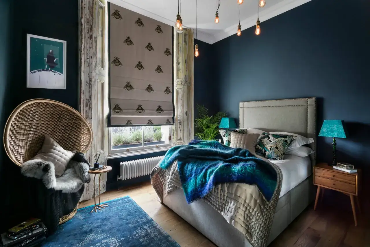 Ein Schlafzimmer in Petrol mit einem flauschigen petrolfarbenen &Uuml;berwurf, der zeigt, welche Farbe passt zu petrol. Ein Korbsessel und eine Biene-Tapete erg&auml;nzen den Look.