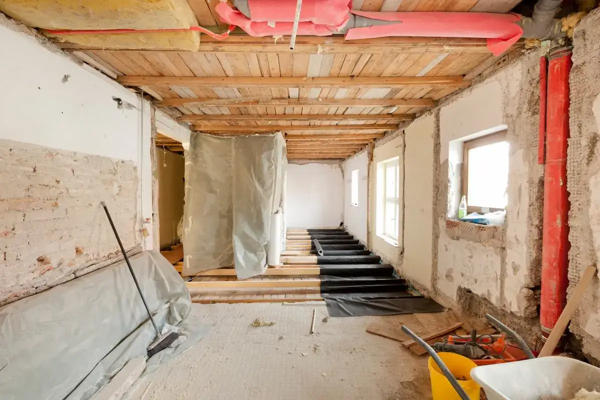 Baustelle mit freiliegenden Balken, D&auml;mmung und Rohren. Dies ist ein Beispiel f&uuml;r eine Kernsanierung, bei der ein Geb&auml;ude von Grund auf renoviert wird.