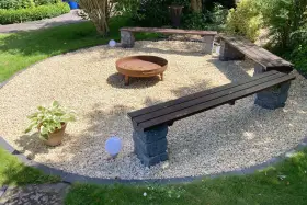 Gemütliche Kies Garten Sitzecke mit Feuerstelle und Bänken. Perfekt für laue Sommerabende.