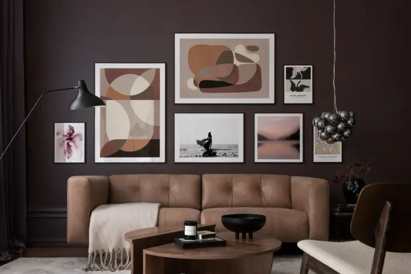 Braune und beige Töne passen wunderbar zu Schwarz. Ein stilvolles Wohnzimmer mit brauner Ledercouch, Kunstwerken und einem Couchtisch.